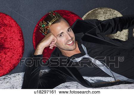 Stock Image - Smiling man wearing plastic crown in bar. Fotosearch