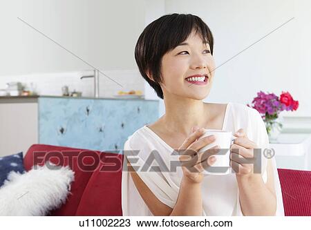 Stock Image - Smiling woman drinking cup of coffee. Fotosearch