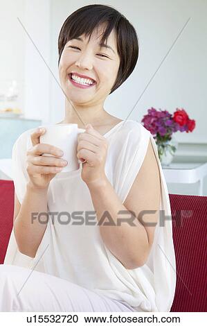 Stock Image - Smiling woman drinking cup of coffee. Fotosearch