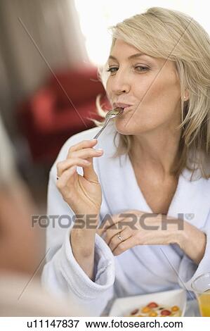 Stock Photo - Smiling woman eating breakfast. Fotosearch