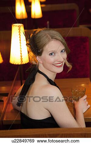 Stock Photo - Smiling woman having drink at restaurant. Fotosearch