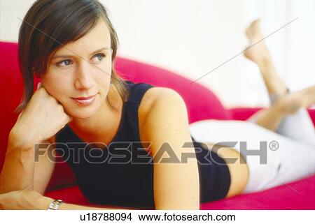 Picture - Smiling woman relaxing on couch. Fotosearch