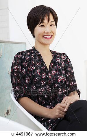 Stock Photo - Smiling woman sitting in modern chair. Fotosearch