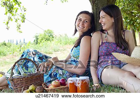 Smiling women picnicking in orchard View Large Photo Image Stock Photo - Smiling women picnicking in orchard. Fotosearch
