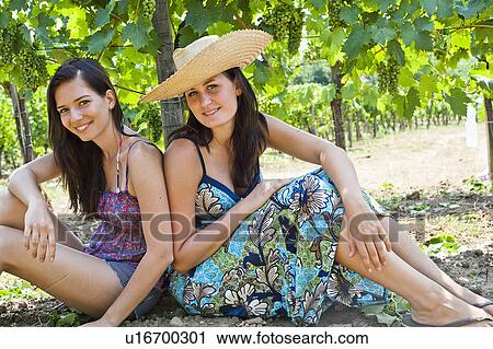 Smiling women sitting by tree in orchard View Large Photo Image Stock Image - Smiling women sitting by tree in orchard. Fotosearch
