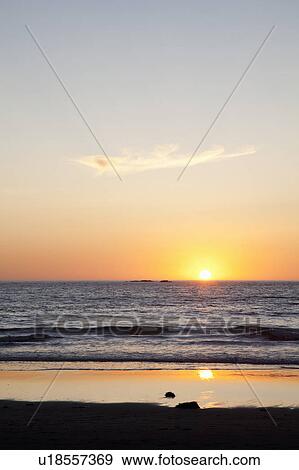 Sun setting over ocean on beach View Large Photo Image Stock Photo - Sun setting over ocean on beach. Fotosearch