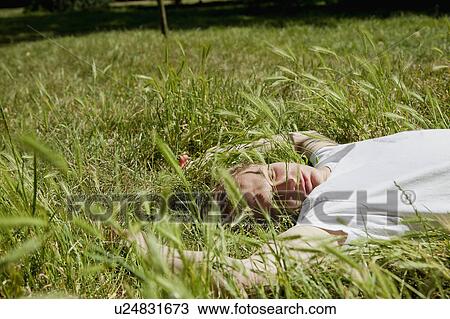 Stock Image - Teenage boy laying in tall grass. Fotosearch