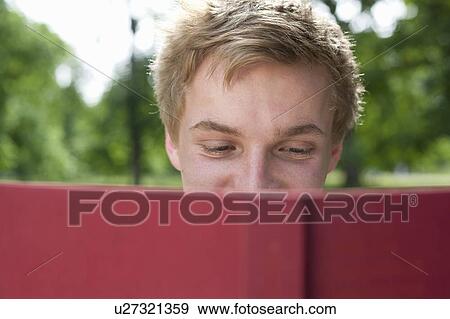 Stock Photo - Teenage boy reading in park. Fotosearch