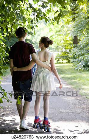 Stock Image - Teenage boy with roller skating girl. Fotosearch