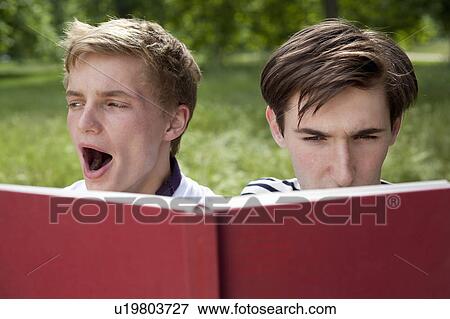 Stock Photo - Teenage boys reading in park. Fotosearch
