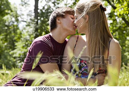 Teenage couple kissing in tall grass View Large Photo Image Stock Image - Teenage couple kissing in tall grass. Fotosearch