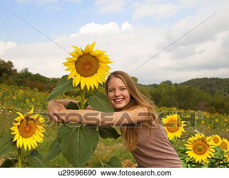 Teenage girl hugging sunflower in field View Large Photo Image Stock Image - Teenage girl hugging sunflower in field. Fotosearch