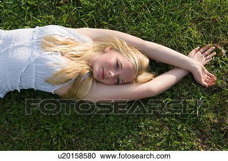 Stock Image - Teenage girl laying in grass. Fotosearch