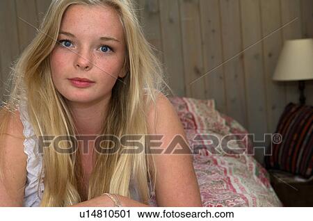 Stock Image - Teenage girl laying on bed. Fotosearch