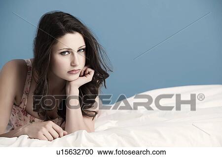 Stock Image - Teenage girl laying on bed. Fotosearch