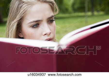 Stock Photo - Teenage girl reading in park. Fotosearch