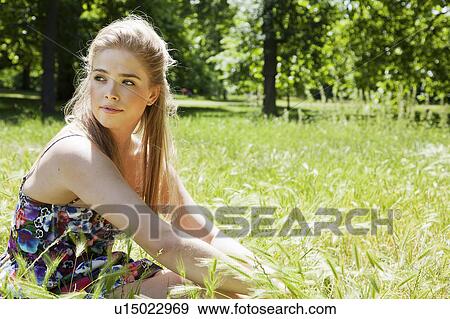 Stock Photo - Teenage girl sitting in tall grass. Fotosearch