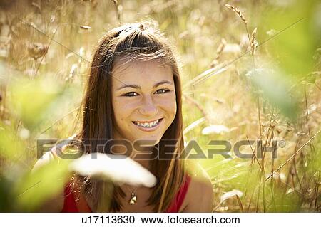 Stock Image - Teenage girl smiling in tall grass. Fotosearch