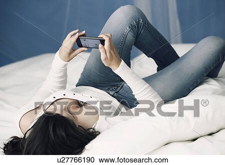 Teenage girl using cell phone on bed View Large Photo Image Stock Image - Teenage girl using cell phone on bed. Fotosearch