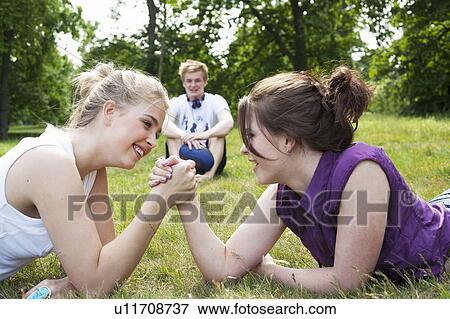 Teenage girls arm wrestling in grass View Large Photo Image Stock Photo - Teenage girls arm wrestling in grass. Fotosearch
