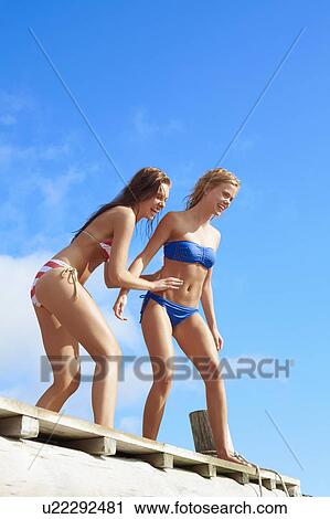 Stock Image - Teenage girls jumping into lake. Fotosearch