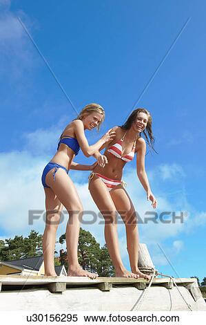 Stock Photography - Teenage girls jumping into lake. Fotosearch