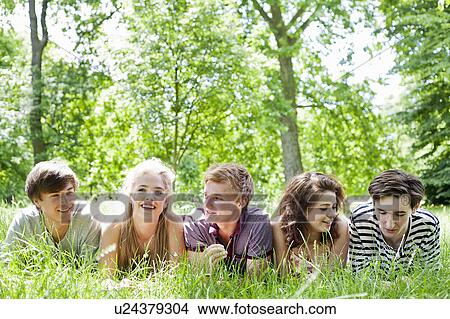 Picture - Teenagers laying in grass in park. Fotosearch