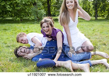 Stock Photo - Teenagers playing in grass in park. Fotosearch