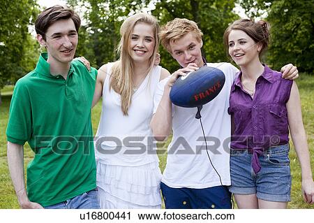 Stock Image - Teenagers standing in park together. Fotosearch
