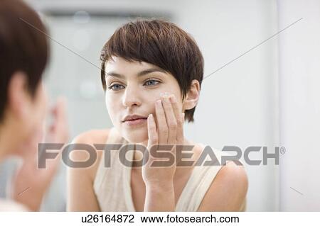 Woman applying moisturizer in mirror View Large Photo Image Stock Image - Woman applying moisturizer in mirror. Fotosearch