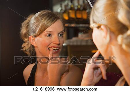Woman checking her teeth in mirror View Large Photo Image Stock Photograph - Woman checking her teeth in mirror. Fotosearch