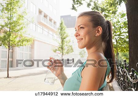 Woman drinking water on park bench View Large Photo Image Stock Image - Woman drinking water on park bench. Fotosearch