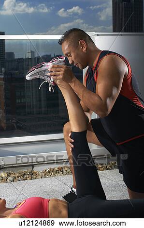 Stock Photo - Woman exercising with trainer on rooftop. Fotosearch