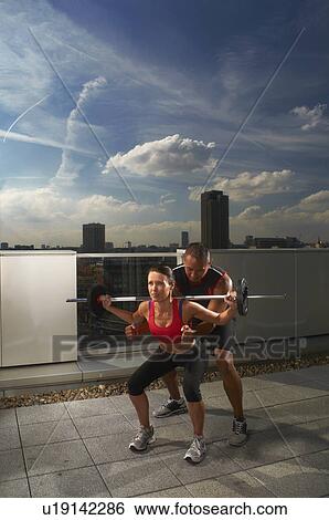 Woman exercising with trainer on rooftop View Large Photo Image Stock Photograph - Woman exercising with trainer on rooftop. Fotosearch
