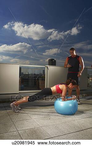 Stock Photography - Woman exercising with trainer on rooftop. Fotosearch