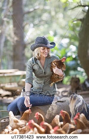 Woman feeding chickens on farm View Large Photo Image Stock Image - Woman feeding chickens on farm. Fotosearch