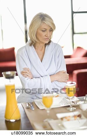 Stock Photography - Woman in bathrobe at breakfast table. Fotosearch