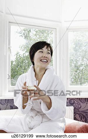 Stock Photo - Woman in bathrobe drinking glass of wine. Fotosearch