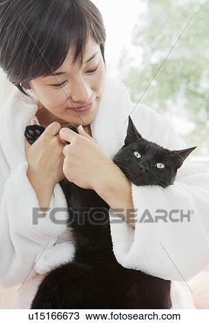 Stock Image - Woman in bathrobe holding cat. Fotosearch