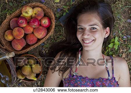 Stock Photograph - Woman laying with baskets of fruit. Fotosearch