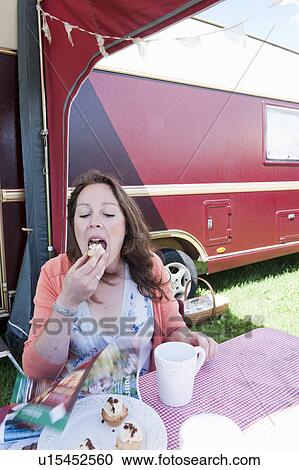 Stock Image - Woman picnicking outside trailer. Fotosearch