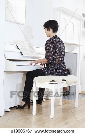 Stock Photo - Woman playing piano at home. Fotosearch