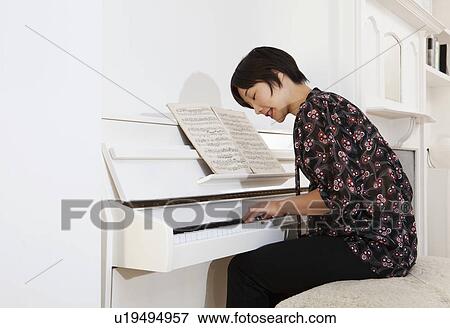 Woman playing piano at home View Large Photo Image Stock Photo - Woman playing piano at home. Fotosearch