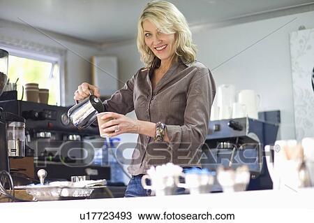 Stock Image - Woman pouring coffee in coffee shop. Fotosearch