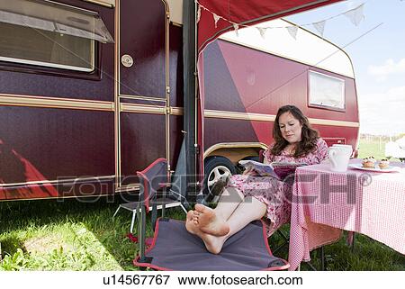 Woman reading magazine outside trailer View Large Photo Image Stock Photo - Woman reading magazine outside trailer. Fotosearch