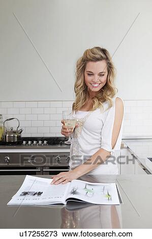 Stock Image - Woman relaxing with wine and magazine. Fotosearch