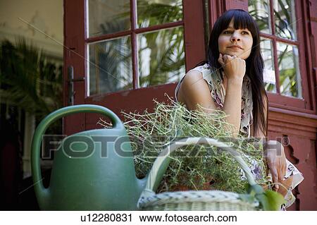 Woman sitting with plants on back porch View Large Photo Image Stock Image - Woman sitting with plants on back porch. Fotosearch