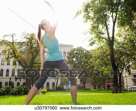 Stock Image - Woman stretching in urban park. Fotosearch