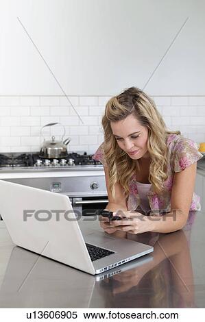 Stock Photography - Woman using laptop and cell phone. Fotosearch