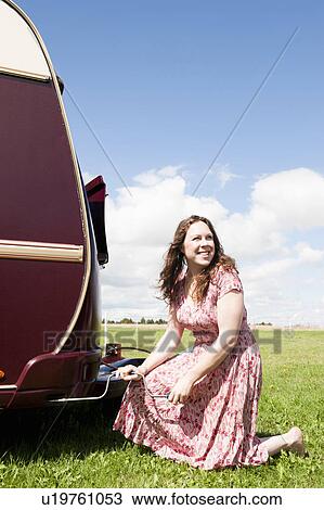 Stock Image - Woman working on trailer in field. Fotosearch